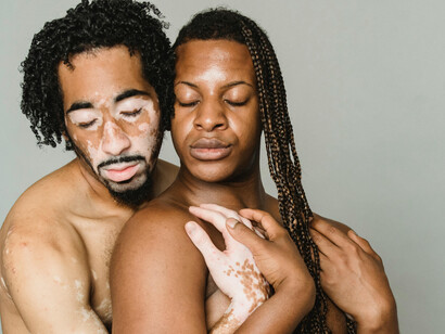 Multiethnic transgender men embracing, shown from the waist up