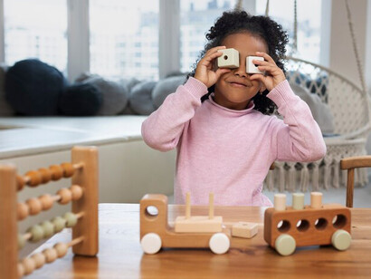 An African American girl enjoying playtime with eco-friendly, gender-neutral toys indoors