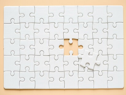 A nearly completed jigsaw puzzle, with one piece lying slightly askew and the space it should occupy visibly empty, representing the search for balance and completion through mediation