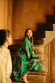 Woman in a green outfit standing on stone stairs 