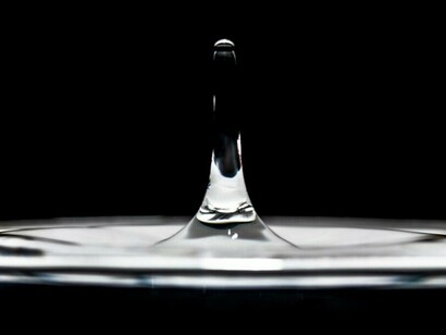 A single drop of water stands out against a soft black-and-white background