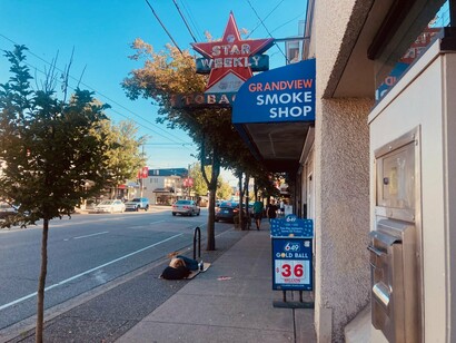 An unhoused person sleeping in front of Grandview Smoke Shop on Commercial Drive, Vancouver, Canada © Photo by John Macanas
