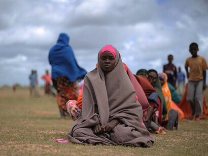 Displaced women sit waiting at a food distribution center in Afgoye, Somalia, as part of a humanitarian aid operation