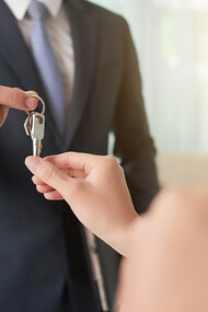 A beaming couple receiving the keys to their new house from a real estate professional, capturing the joy of homeownership
