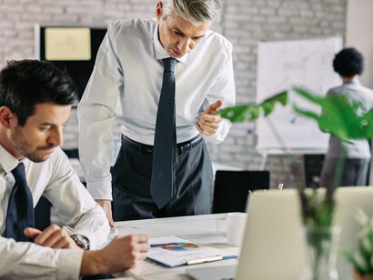 Due uomini d'affari analizzano dei documenti e le statistiche di un progetto mentre lavorano in ufficio