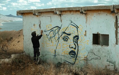 An expressive artist spray-painting the wall of an abandoned building, embodying the spirit of a creative soul