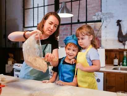 Happy children cooking with their mother in the kitchen