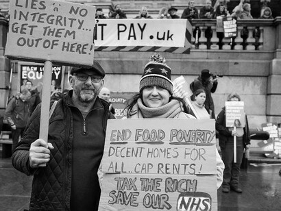 Two people with placards in Trafalgar Square during a rally on Saturday 6 November against austerity, and also for climate and social justice, UK
