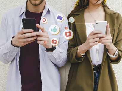 A couple standing side by side immersed in their phones, completely engrossed in their own digital worlds and oblivious to the world around them, highlighting the struggle to disconnect. 