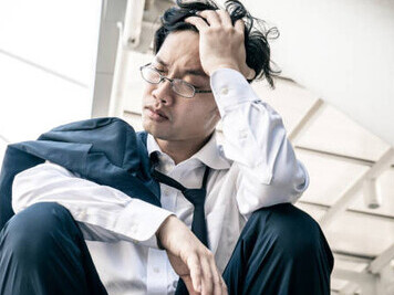 An adult struggling with anxiety and depression feels overwhelmed by life, burdened by sadness, loneliness, worry, and the impacts of racism and discrimination