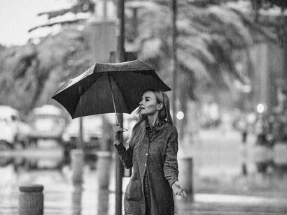 A woman walking alone on a quiet street, holding an umbrella