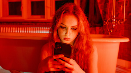 A teenager with a smudged face holding a cellphone, sitting on the bathroom floor—evoking the emotional isolation, digital dependency, and silent distress that many adolescents experience in today’s online world