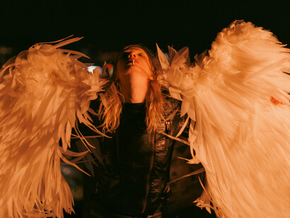 A woman with feathered angel wings in a dramatic night scene