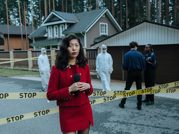 A woman in a red outfit reporting from a crime scene as a journalist