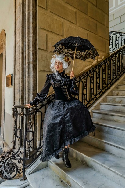 Baroque elegance captured as a woman poses in ornate costume against a backdrop of classic architecture