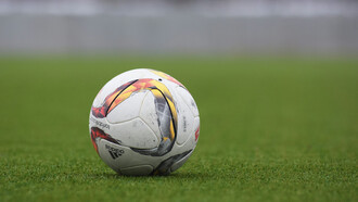 An Adidas soccer ball resting on the grass pitch, ready for the game