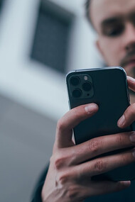 Man wearing black sweater using smartphone