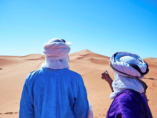 Two travellers gazing across the desert in M'hamid El Ghizlane, representing the quiet allure of the Sahara’s vast and timeless horizons