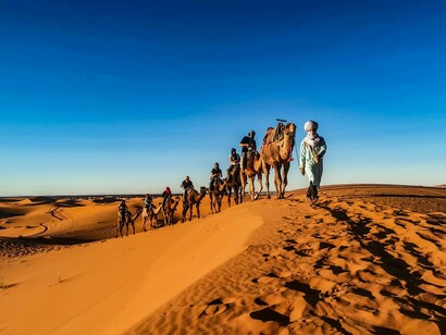 People on camels crossing the Moroccan desert, illustrating a diplomatic approach rooted in continuity and strategic patience