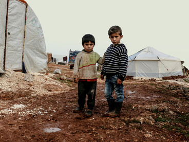 Young boys standing in a refugee campsite in Syria, capturing the human impact of conflict and displacement