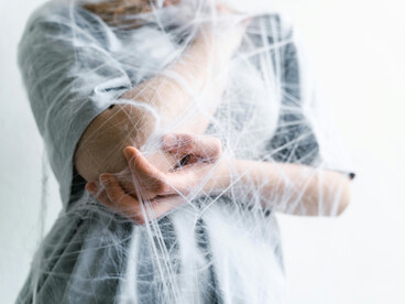 A human figure wrapped in webs, reflecting the invisible grip of inherited fears and cultural narratives
