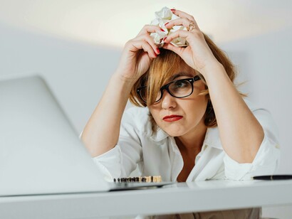 A short-haired woman leans on a table, embodying information overload and cognitive exhaustion in contemporary life