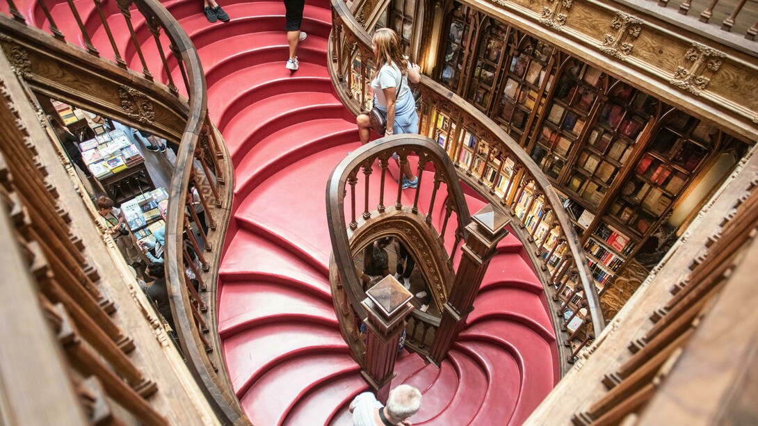 Interior da Livraria Lello no Porto, Portugal. Naturalmente, nessa imbricação entre arte, história e geografia, não nos surpreende a cartografia do nosso imaginário através da composição de rotas de viagem, itinerários cristalizando todo um imaginário específico: as de peregrinação (o Caminho de Santiago, p. ex., do séc. IX, a Jerusalém, que se simboliza e miniaturiza nos Montes Sacros), as místicas e enigmáticas (o Caminho ou a Linha Sagrada de São Miguel Arcanjo, da Irlanda a Israel, com 7 santuários a ele dedicados), as de objectos mágicos (a do Graal, de Jerusalém à Península Ibérica), as dos Contos de Fadas (com destaque para a alemã, com c. 600 Km e 60 municípios entre Hanau, onde nasceram Jacob e Wilhelm Grimm, e Bremen, do conto “Os músicos de Bremen”),  e tantas outras relacionando elementos temática ou estilisticamente (a do Românico, do Gótico, etc.) afins