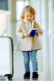 Menina feliz com mala e passaporte no corredor do aeroporto