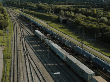 A long freight train crosses the scenic countryside, symbolizing the vital rail connection between Europe and Asia