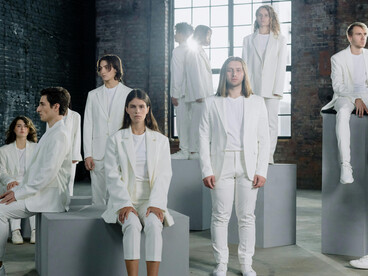 Models in white attire walking indoors during a fashion sho