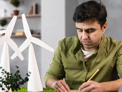 A man contemplates an eco-friendly wind power project, standing before wind turbines that symbolize renewable energy investment