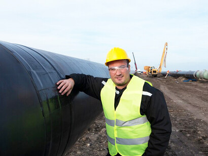 A close-up shot of an industrial worker beside a gas pipeline at a construction site
