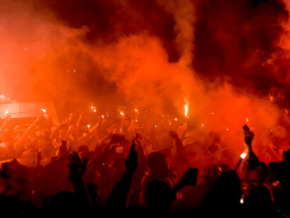 Silhouetted figures standing in the smoke-filled street during nighttime protests