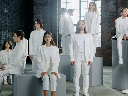 Models in white attire walking indoors during a fashion sho