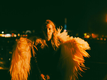 Woman wearing feathered angel wings in a dramatic nighttime setting