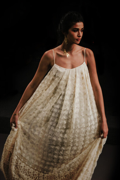 A stylish woman confidently walks the runway during a high-profile fashion show, showcasing the latest trends and designs