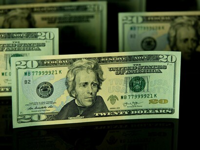 Layered dollar bills illuminated against a dark setting, symbolizing the financial interests that often shape political decisions