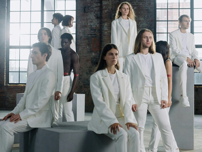 People in white outfits walking indoors at a fashion show