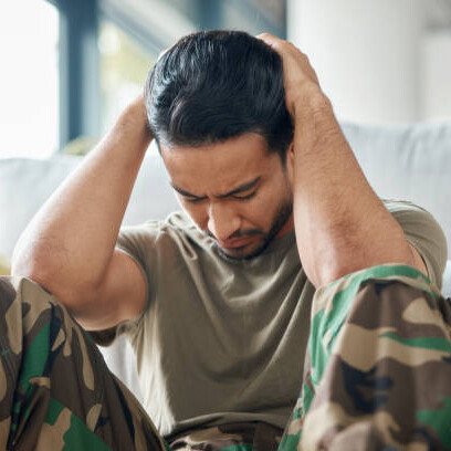 A military veteran sitting alone on a sofa, struggling with memories of war — symbolizing emotional pain, fear, and post-traumatic stress