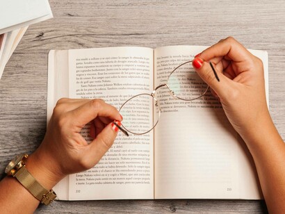 Donna che legge un libro tenendo un paio di occhiali tra le mani: "il refuso rompe la perfezione asettica, ma al contempo ci ricorda che dietro a quelle pagine ci sono mani, occhi, stanchezze. E forse è proprio quel refuso che rende più vera la voce dell’autore"