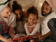 Família brasileira interracial desfrutando da leitura de um livro físico juntos