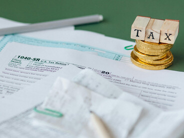 Tax papers spread out on the table alongside some coins