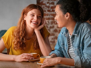 Due persone che ridono al tavolino di un bar: "Sin dalla nostra comparsa sulla Terra, e per tutto il nostro lungo percorso evolutivo, abbiamo sviluppato un linguaggio — prima attraverso i gesti, poi con la voce e infine anche con la scrittura — che potesse essere condiviso unicamente con altri esseri umani..."