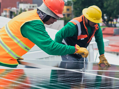 Technicians mounting solar panels on the roof of a building