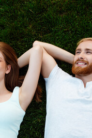 Una coppia felice, un uomo e una donna, giacciono sull'erba sorridendo