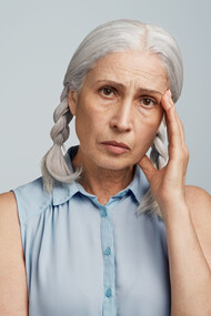 A senior woman with pigtails, dressed in a blue blouse, representing the experience of living with Alzheimer