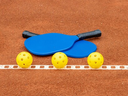 The straightforward setup of two paddles and a few balls on a court represents the ease of learning pickleball, a sport that's easy to pick up, provides an excellent aerobic workout, and is known for its friendly, inclusive atmosphere