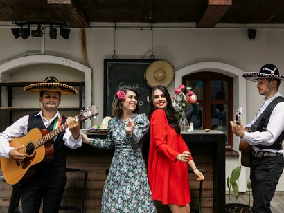 A woman dances in a flowing dress while men in sombreros play guitars beside her