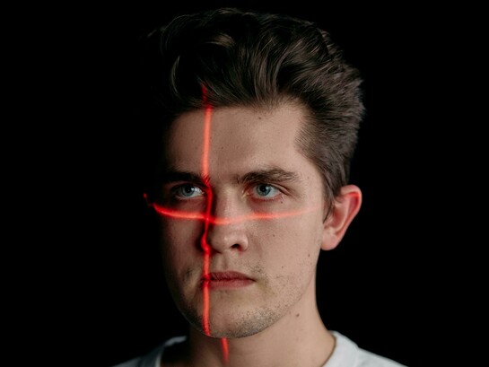 Portrait of a man with laser lines on his face, symbolizing facial recognition technology
