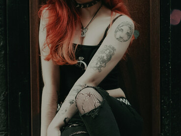 A tattooed woman with dyed hair wearing a crop top, embodying rebellious youth fashion